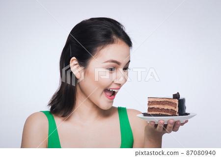 Beautiful smiling asian young woman with a chocolate cake isolated on white background. 87080940