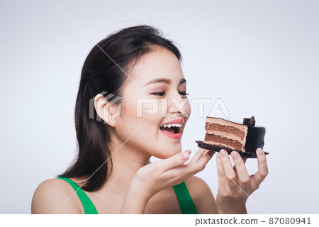 Beautiful smiling asian young woman with a chocolate cake isolated on white background. 87080941