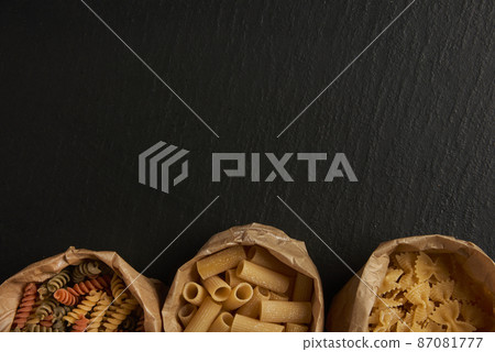 pasta concept three types of pasta put into paper bags on the black background 87081777