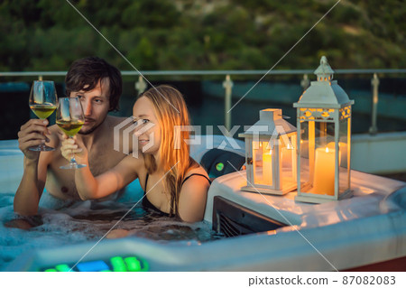Portrait of young carefree happy smiling couple relaxing at hot tub during enjoying happy traveling moment vacation life against the background of green big mountains 87082083