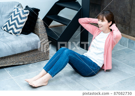 Young woman doing abdominal muscle training in the living room 87082730