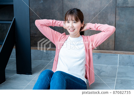 Young woman doing abdominal muscle training in the living room 87082735