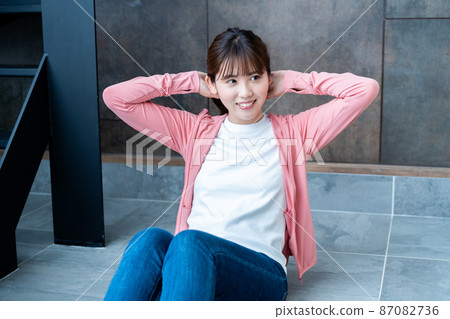 Young woman doing abdominal muscle training in the living room Young woman doing abdominal muscle training in the living room 87082736
