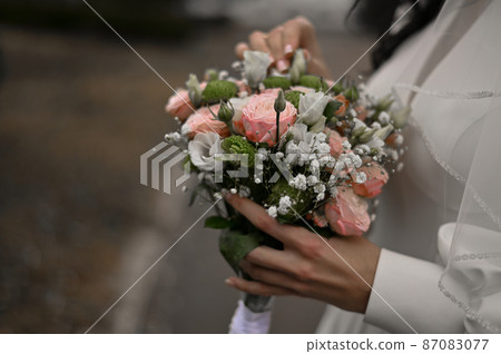 a beautiful wedding bouquet in the hands of the bride 87083077