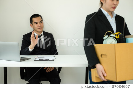 A woman office worker is unhappy with being fired from a company packing things into cardboard boxes. The Young woman was stressed and disappointed by being fired. concept of layoffs and unemployment A woman office worker is unhappy with being fired from a company packing things into cardboard boxes. The Young woman was stressed and disappointed by being fired. concept of layoffs and unemployment 87084607