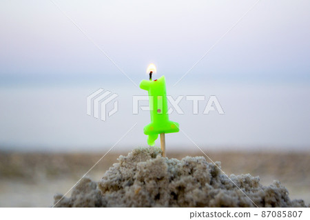Candle number one on stick inserted into sand and burns. Lighted candle Candle number one on stick inserted into sand and burns. Lighted candle 87085807