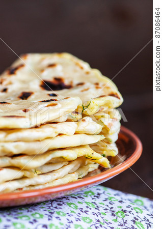 Stack of Khychin - traditional flatbreads stuffed with mashed potatoes and greens served on a plate. Stack of Khychin - traditional flatbreads stuffed with mashed potatoes and greens served on a plate. 87086464