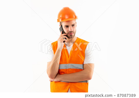 man in orange reflective vest and helmet has phone call isolated on white background, architect 87087389