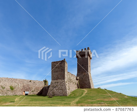 View from beneath up to The Rocca of Radicofani fort and thick brick walls remain, Tuscany, Italy 87087763
