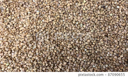 Buckwheat tea in a wooden spoon on a light wooden background. Buckwheat tea close-up macro photography. Scattered buckwheat tea pellets on wooden background 87090655