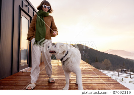 Woman with her dog resting on terrace of tiny house on nature 87092319