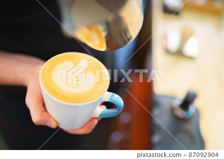barista pouring milk into espresso coffee for making cappuccino, latte art 87092904