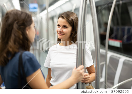Two girlfriends talk in a subway car 87092905