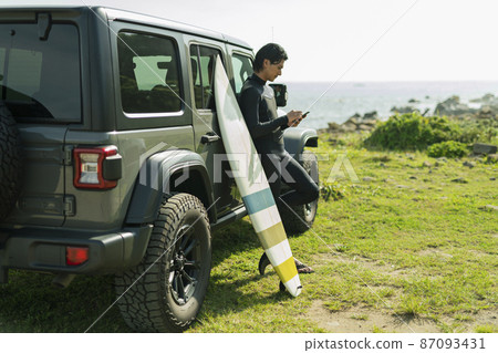 A man checking his cell phone while surfing A man checking his cell phone while surfing 87093431
