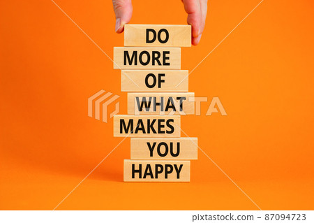 Do what makes you happy symbol. Wooden blocks with words 'Do more of what makes you happy'. Businessman hand. Beautiful orange background, copy space. Business, do what makes you happy concept. 87094723
