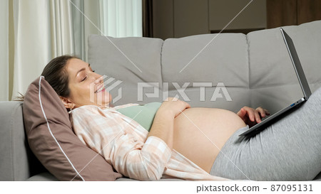 Pregnant mother does online shopping for baby lying on sofa Pregnant mother does online shopping for baby lying on sofa 87095131