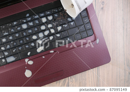 tea spilling over a laptop keyboard on table  87095149