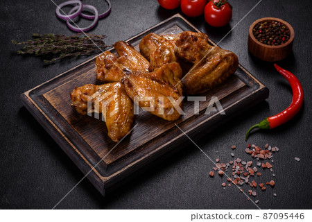 Baked chicken wings with vegetables and spices on a black background Baked chicken wings with vegetables and spices on a black background 87095446