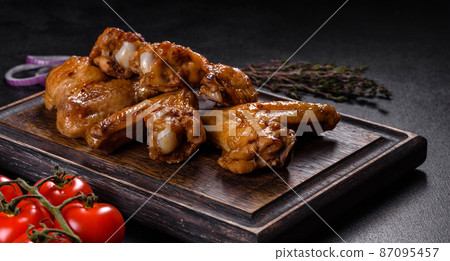 Baked chicken wings with vegetables and spices on a black background Baked chicken wings with vegetables and spices on a black background 87095457