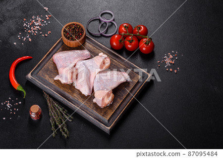 Chicken wings lie on a wooden board on a black background 87095484