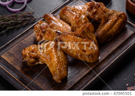 Baked chicken wings with vegetables and spices on a black background 87095501