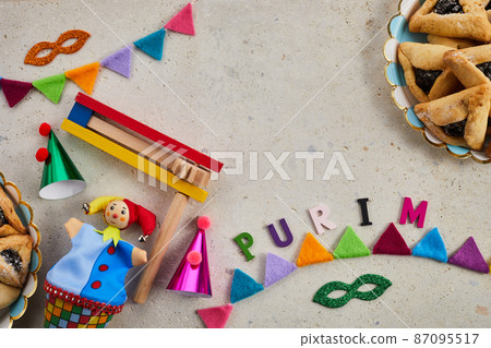 Jewish holiday Purim background with hamantaschen or hamans ears cookies, carnival mask and noisemaker Jewish holiday Purim background with hamantaschen or hamans ears cookies, carnival mask and noisemaker 87095517