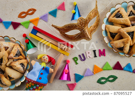 Jewish holiday Purim background with hamantaschen or hamans ears cookies, carnival mask and noisemaker 87095527