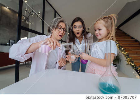 Family doing chemical experiment, mixing flasks indoors Family doing chemical experiment, mixing flasks indoors 87095707