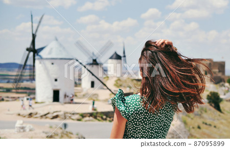 Rear view woman posing against windmills in Consuegra town. Spain 87095899
