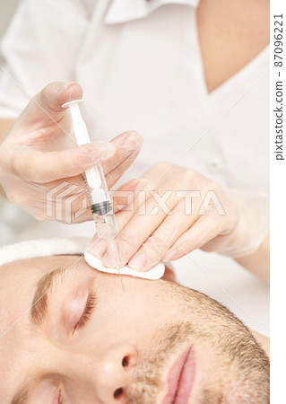 Injection at spa salon. Doctor hands in gloves. Closeup. Pretty male patient Injection at spa salon. Doctor hands in gloves. Closeup. Pretty male patient 87096221