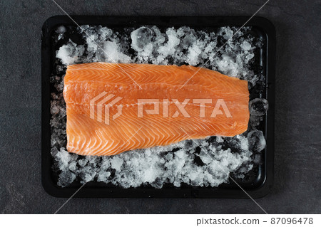 Fresh raw salmon fish fillet on ice on black background top view. Fresh raw salmon fish fillet on ice on black background top view. 87096478