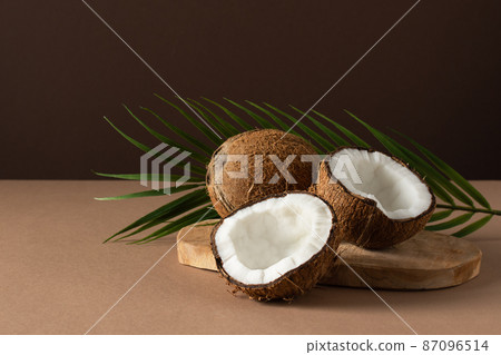 Coconuts with palm leaf over brown background. 87096514