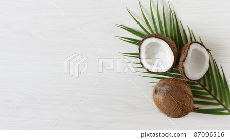Coconuts with palm leaf on white wooden background. Coconuts with palm leaf on white wooden background. 87096516