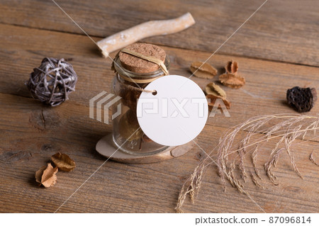 Round white tag mockup on glass jar with dry perfume a wooden background with boho decoration, element for packing 87096814