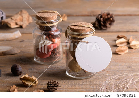 Round white tag mockup on glass jar with dry perfume a wooden background with boho decoration, element for packing Round white tag mockup on glass jar with dry perfume a wooden background with boho decoration, element for packing 87096821