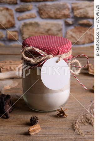 The Round white gift tag mockup on a jar with mixture of ingredients for baking cookies for Christmas 87096829