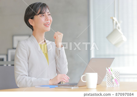 Business woman looking out the window with a guts pose 1 87097084