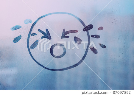 doodle drawn sad face on foggy glass window raindrops blue color concept photo doodle drawn sad face on foggy glass window raindrops blue color concept photo 87097892