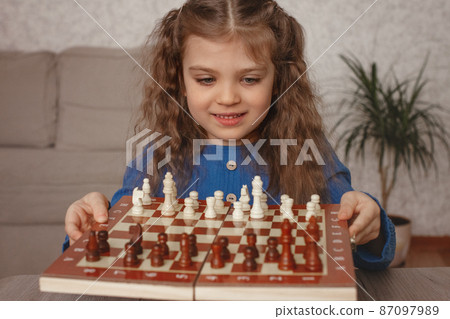 smiling little girl 5 years old holding chessboard with wooden chess smiling little girl 5 years old holding chessboard with wooden chess 87097989