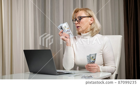 Elderly woman counts and distributes money to pay bills Elderly woman counts and distributes money to pay bills 87099235