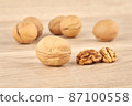 Walnuts on a wooden background, whole and peeled walnut in the foreground 87100558