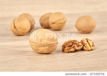 Walnuts on a wooden background, whole and peeled walnut in the foreground 87100558
