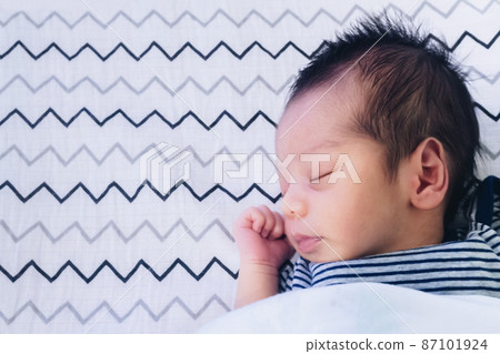 close up of cute little newborn asian baby boy sleeping on bed at children bedroom with copy space. family, healthy, life and relationship concept. 87101924