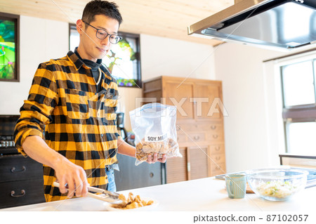 A health-conscious man who uses tongs to serve soy meat from a bag to a plate A health-conscious man who uses tongs to serve soy meat from a bag to a plate 87102057