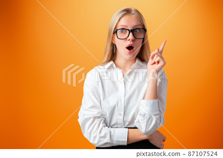Portrait of cute thoughtful teen girl against orange background Portrait of cute thoughtful teen girl against orange background 87107524