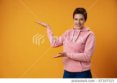 Young woman with short hair over studio color background pointing finger to the side 87107525