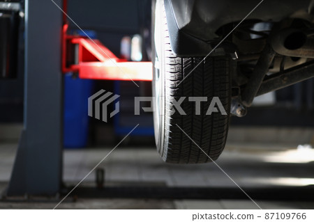 Automobile tire, part of automobile in service center, lifted car in air 87109766