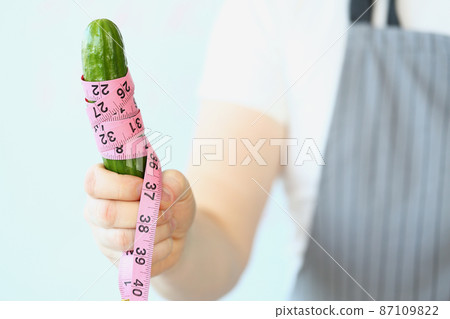Person hold cucumber with measure tape around, diet and healthy and organic food Person hold cucumber with measure tape around, diet and healthy and organic food 87109822