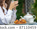 Woman drinking coffee with croissants 87110459