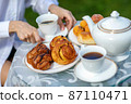Woman drinking coffee with croissants 87110471